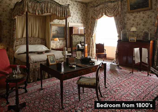 Shows a bedroom in an historical home, decorated in a style from the 1800's.