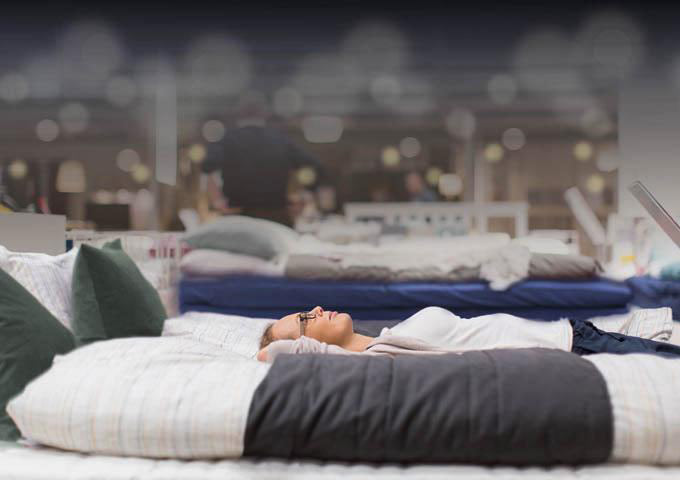 Woman lies on mattress in mattress store to try it out