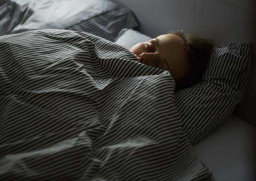 Woman sleeps with quilt gathered up around her face