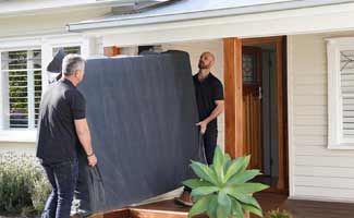 Mattress delivery men carefully install mattress in home
